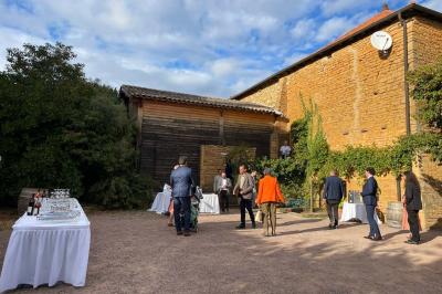 Bouteille de vin rouge posée sur une surface en pierre, avec des fleurs floues et un paysage en arrière-plan.