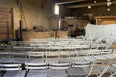 Bouteille de vin rouge posée sur une surface en pierre, avec des fleurs floues et un paysage en arrière-plan.