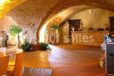 Bouteille de vin rouge posée sur une surface en pierre, avec des fleurs floues et un paysage en arrière-plan.