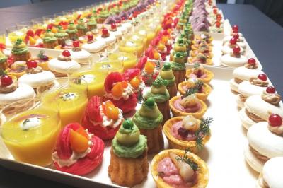 Tables dressées avec nappes beiges, décorées de bouquets de fleurs et d'ustensiles en bois, devant des volets bleus.