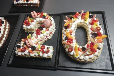Tables dressées avec nappes beiges, décorées de bouquets de fleurs et d'ustensiles en bois, devant des volets bleus.
