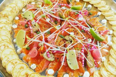 Tables dressées avec nappes beiges, décorées de bouquets de fleurs et d'ustensiles en bois, devant des volets bleus.
