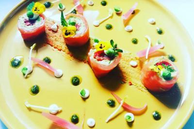 Tables dressées avec nappes beiges, décorées de bouquets de fleurs et d'ustensiles en bois, devant des volets bleus.