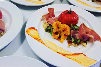 Tables dressées avec nappes beiges, décorées de bouquets de fleurs et d'ustensiles en bois, devant des volets bleus.