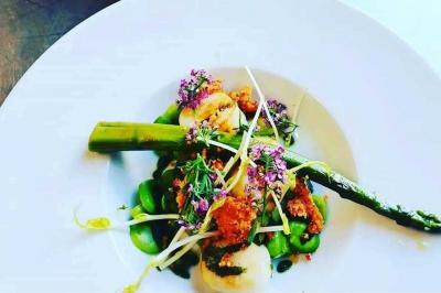 Tables dressées avec nappes beiges, décorées de bouquets de fleurs et d'ustensiles en bois, devant des volets bleus.