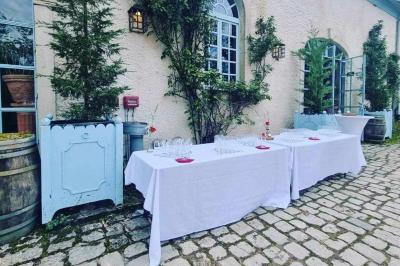 Tables dressées avec nappes beiges, décorées de bouquets de fleurs et d'ustensiles en bois, devant des volets bleus.