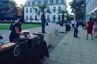 Tables dressées avec nappes beiges, décorées de bouquets de fleurs et d'ustensiles en bois, devant des volets bleus.