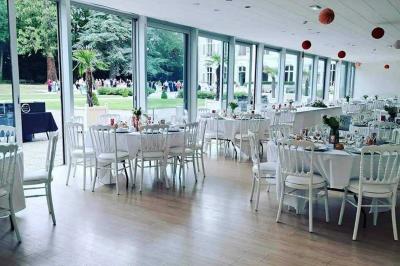 Tables dressées avec nappes beiges, décorées de bouquets de fleurs et d'ustensiles en bois, devant des volets bleus.