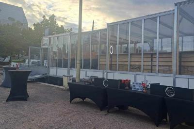 Tables dressées avec nappes beiges, décorées de bouquets de fleurs et d'ustensiles en bois, devant des volets bleus.