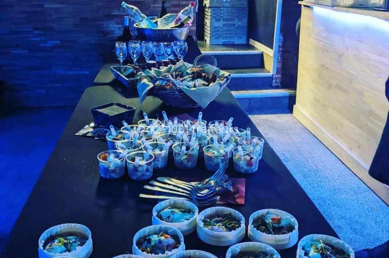 Table de buffet avec verrines, paniers de pain, couverts et verres à vin, dans une ambiance lumineuse tamisée.