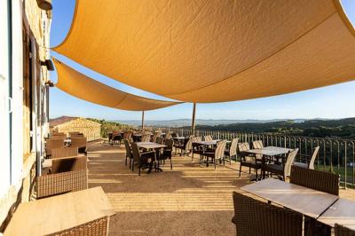 Cour pavée entourée de murs en pierre, avec des plantes en pot et une porte voûtée blanche.