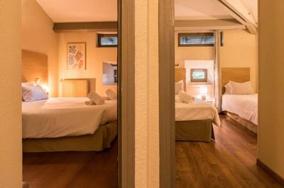 Cour pavée entourée de murs en pierre, avec des plantes en pot et une porte voûtée blanche.