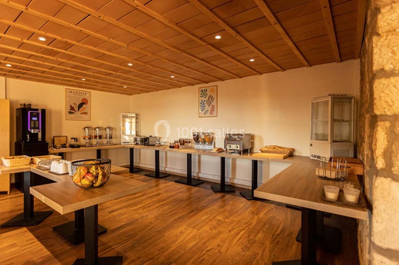 Salle de petit-déjeuner avec buffet comprenant boissons, viennoiseries, céréales et autres aliments disposés sur des tables.