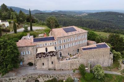 Cour pavée entourée de murs en pierre, avec des plantes en pot et une porte voûtée blanche.