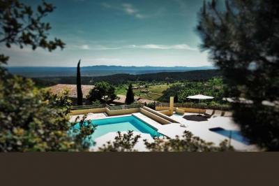 Cour pavée entourée de murs en pierre, avec des plantes en pot et une porte voûtée blanche.