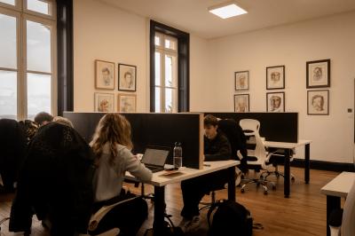 Deux chaises de bureau autour d'une table blanche dans une pièce lumineuse avec parquet et vue sur un jardin.