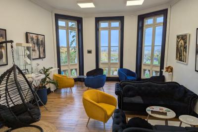 Deux chaises de bureau autour d'une table blanche dans une pièce lumineuse avec parquet et vue sur un jardin.