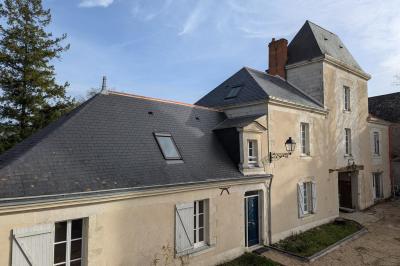 Salle élégante avec tables rondes dressées, chaises rouges et dorées, grand miroir doré et orchidées en décoration.