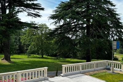 Salle élégante avec tables rondes dressées, chaises rouges et dorées, grand miroir doré et orchidées en décoration.