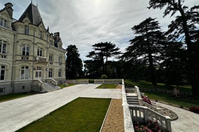 Salle élégante avec tables rondes dressées, chaises rouges et dorées, grand miroir doré et orchidées en décoration.