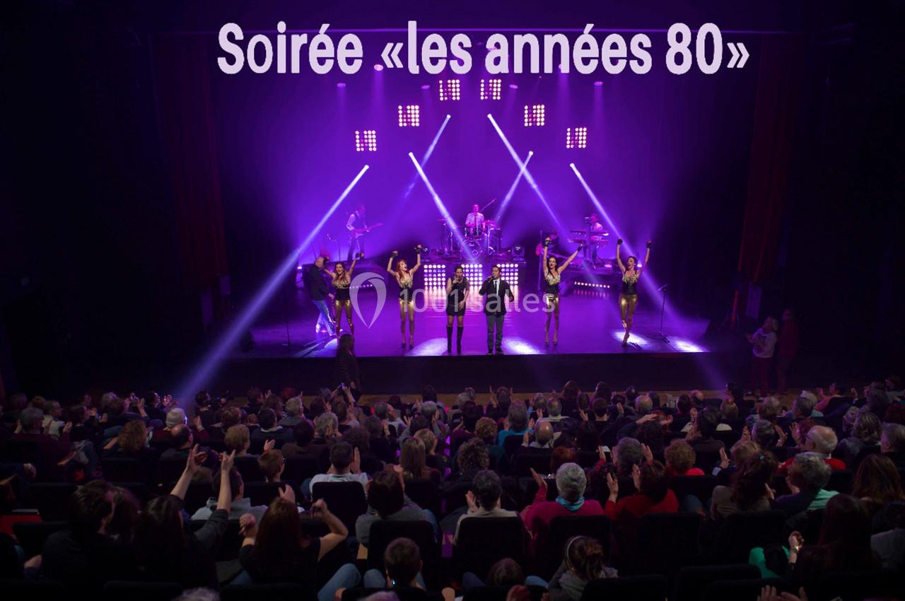 Spectacle sur le thème des années 80 avec musiciens et danseurs sur scène, devant un public nombreux.