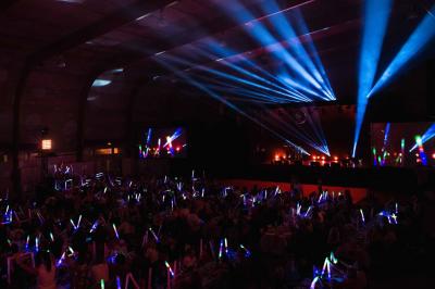 Portraits scintillants de deux figures célèbres réalisés en paillettes sur des panneaux noirs, exposés sur une scène.