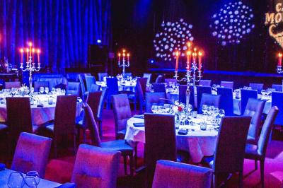 Portraits scintillants de deux figures célèbres réalisés en paillettes sur des panneaux noirs, exposés sur une scène.