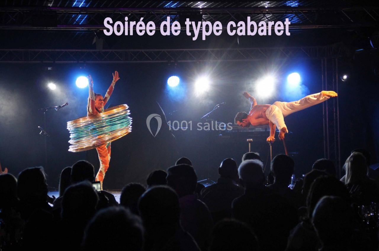 Deux artistes exécutent des performances acrobatiques sur scène lors d'une soirée cabaret, devant un public.