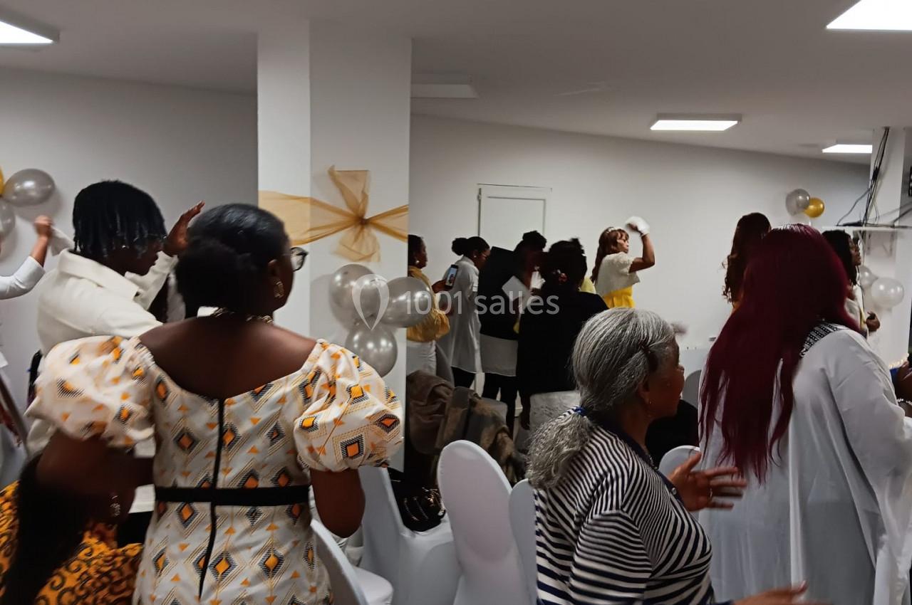 Des personnes participent à un événement festif en intérieur, avec des décorations de ballons et des tenues colorées.