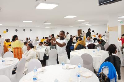 Rangées de chaises rouges alignées dans une salle vide avec un sol en béton et des murs blancs.