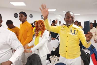 Rangées de chaises rouges alignées dans une salle vide avec un sol en béton et des murs blancs.