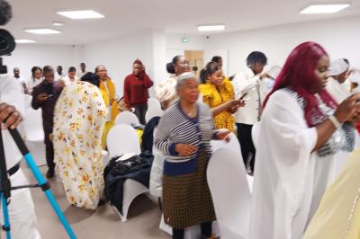 Rangées de chaises rouges alignées dans une salle vide avec un sol en béton et des murs blancs.