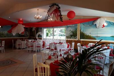 Tente avec table dressée pour un buffet, entourée de chaises blanches, installée sur une pelouse avec haies en arrière-plan.