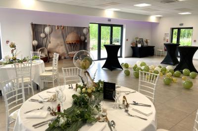 Homme concentré cuisinant en extérieur sur une plancha, entouré de végétation sous un ciel nuageux.