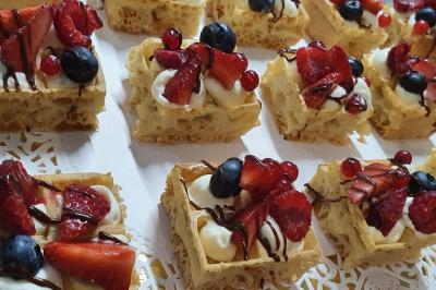 Homme concentré cuisinant en extérieur sur une plancha, entouré de végétation sous un ciel nuageux.