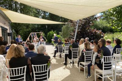 Homme concentré cuisinant en extérieur sur une plancha, entouré de végétation sous un ciel nuageux.