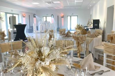 Homme concentré cuisinant en extérieur sur une plancha, entouré de végétation sous un ciel nuageux.