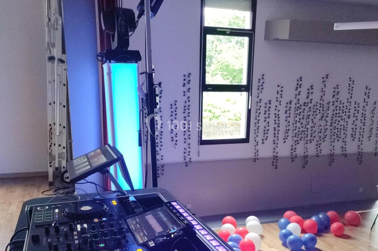 Équipement de DJ installé dans une salle avec des ballons au sol et une fenêtre donnant sur l'extérieur.