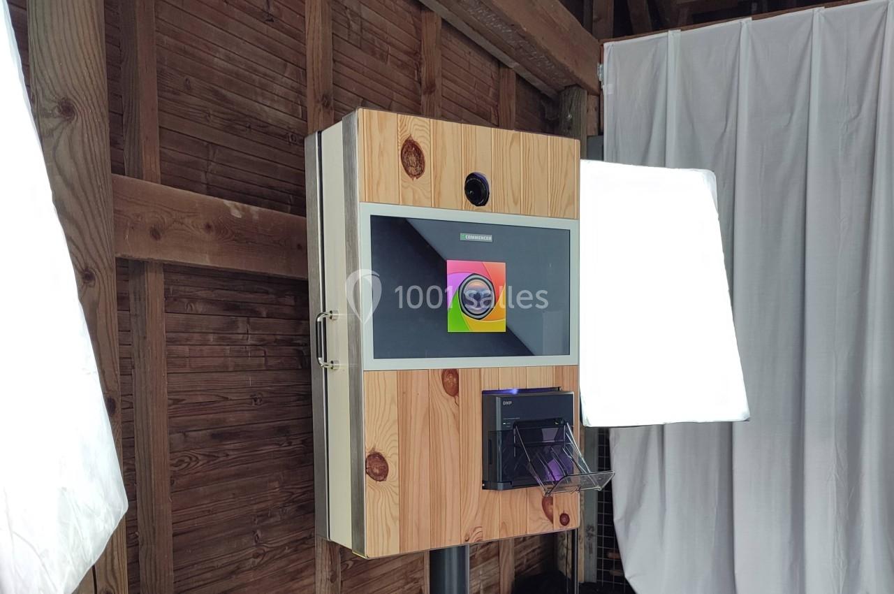 Borne photo en bois avec écran tactile, imprimante intégrée et éclairage, installée dans un espace intérieur.