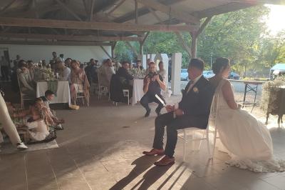 Un DJ mixe dans une salle éclairée par des lumières colorées, avec des tables hautes et un décor sobre.