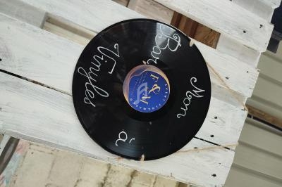 Disque vinyle noir personnalisé avec des inscriptions blanches, posé sur une palette en bois clair.