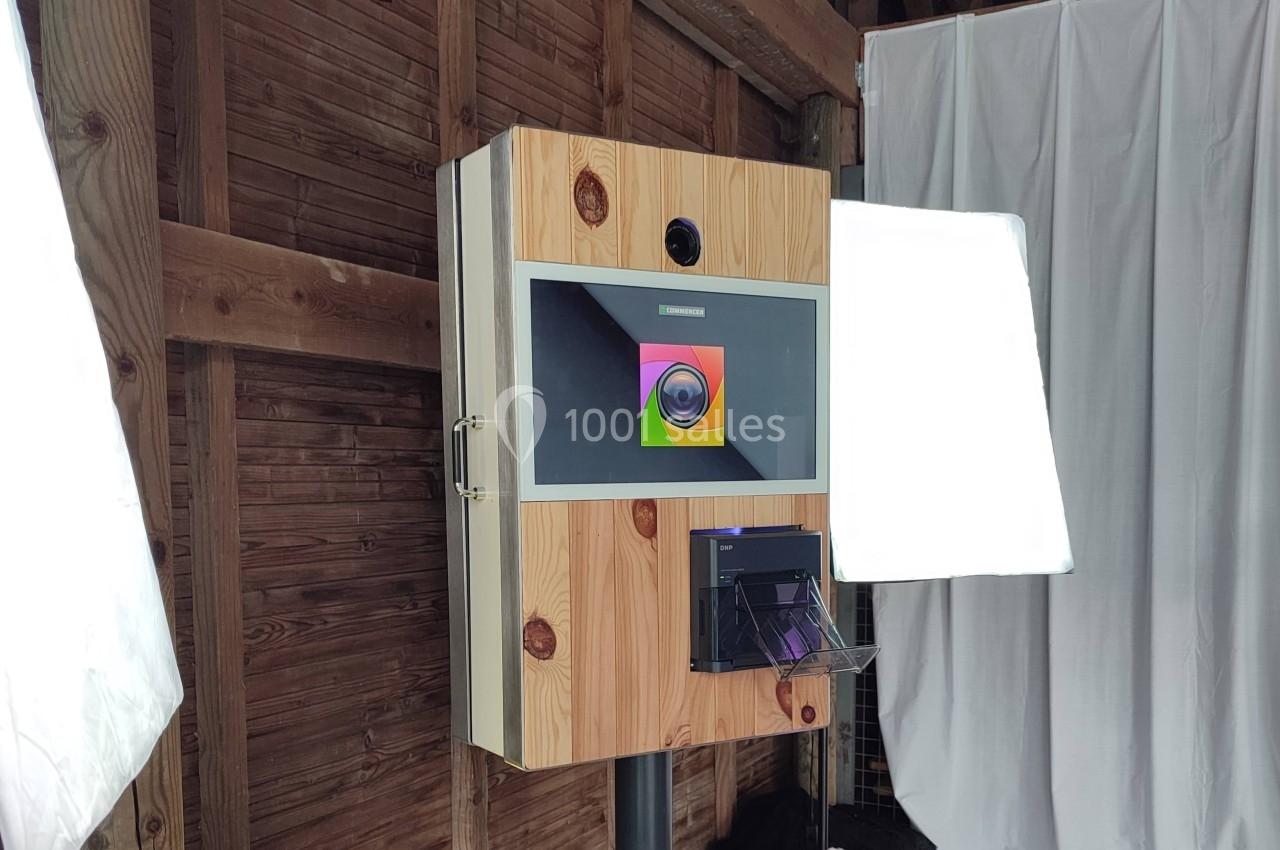 Borne photo en bois avec écran, appareil photo intégré et imprimante, installée dans un espace intérieur en bois.