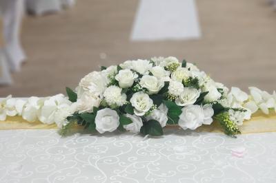 Centre de table en métal doré avec un bouquet de roses blanches et roses, sur une table de réception décorée.