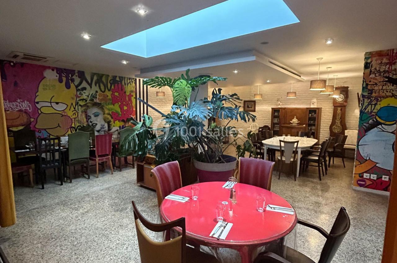 Salle de restaurant moderne avec des murs décorés de graffitis colorés, des plantes et des tables dressées.