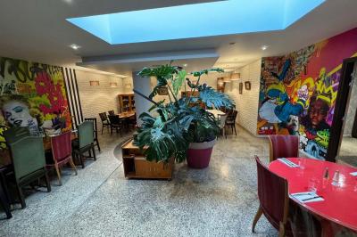 Terrasse d'un café avec des tables et des chaises colorées devant une façade vitrée portant l'inscription ’Au Bout du Bar’.