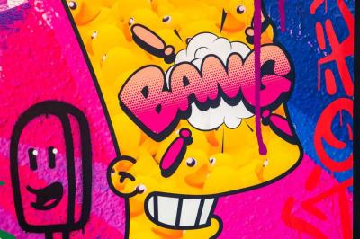 Terrasse d'un café avec des tables et des chaises colorées devant une façade vitrée portant l'inscription ’Au Bout du Bar’.