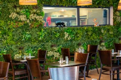 Terrasse d'un café avec des tables et des chaises colorées devant une façade vitrée portant l'inscription ’Au Bout du Bar’.