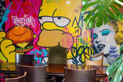 Terrasse d'un café avec des tables et des chaises colorées devant une façade vitrée portant l'inscription ’Au Bout du Bar’.