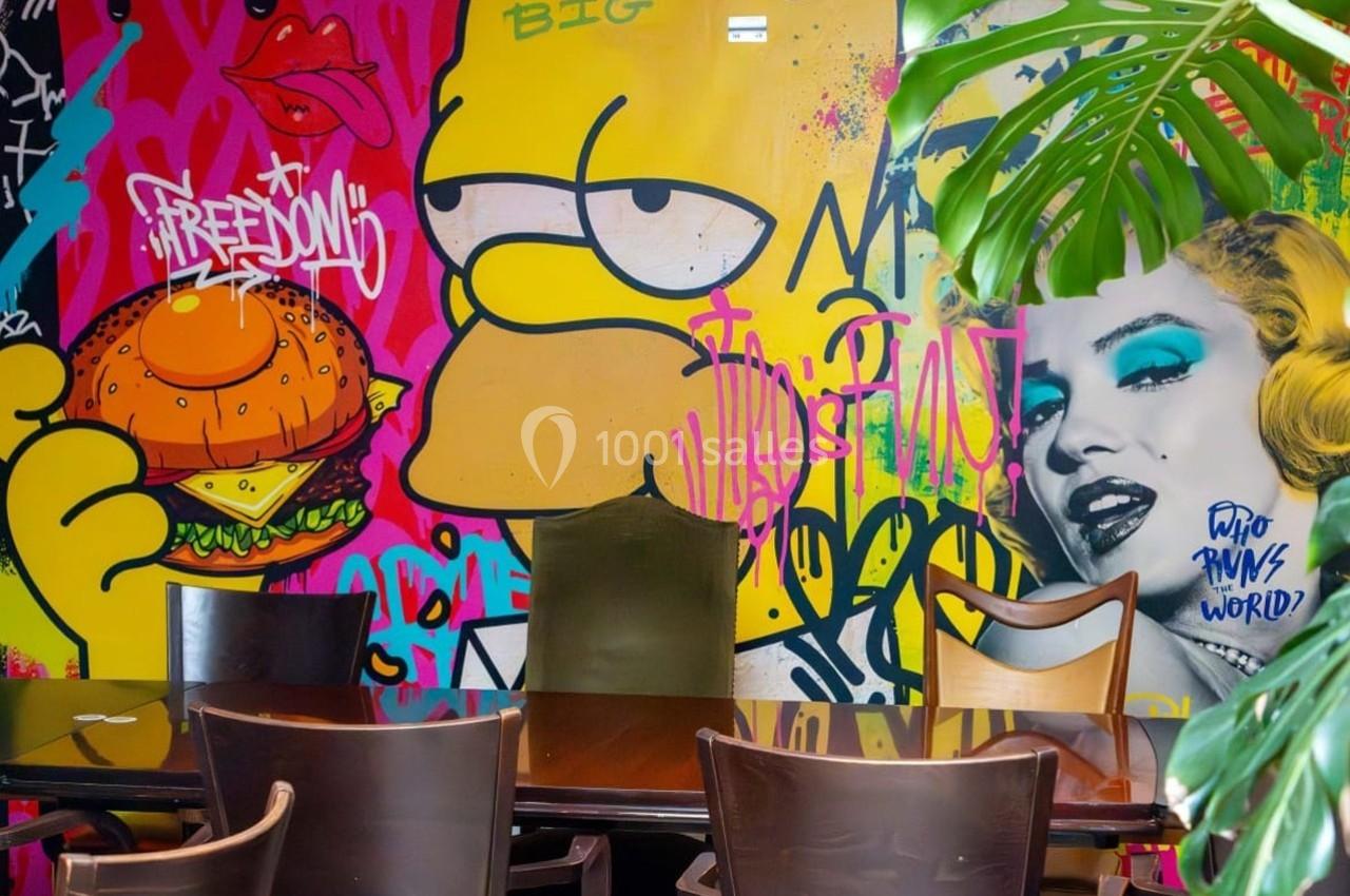 Fresque colorée avec des graffitis, un personnage de dessin animé, un portrait féminin et des plantes en premier plan.