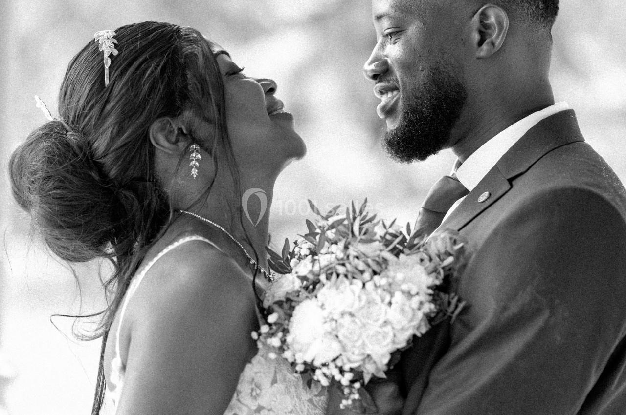 Un couple en tenue de mariage s'enlace et se regarde avec tendresse dans un cadre extérieur flou.